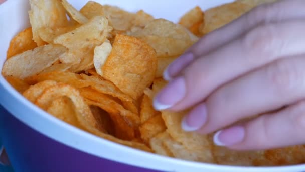 schöne gepflegte Frauenhände mit französischer Maniküre essen Kartoffelchips von einem riesigen Teller auf der Couch - Filmmaterial, Video