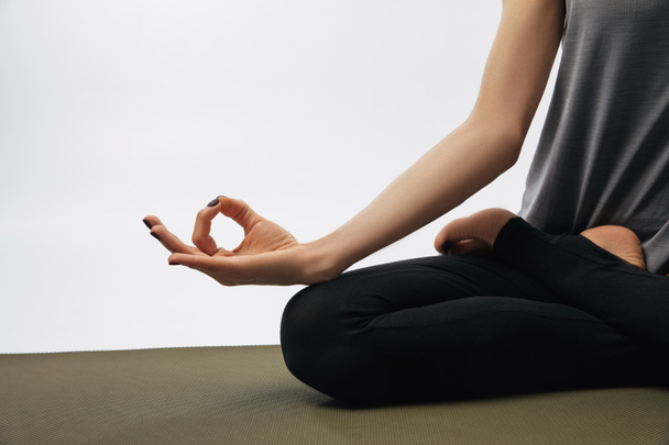 cropped image of woman meditating in yoga lotus pose isolated on white - Foto, afbeelding