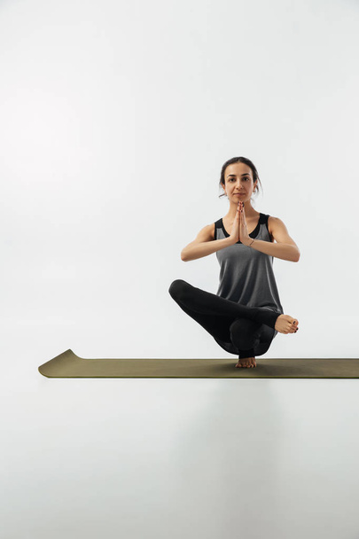 menina praticando pé pé no tapete de ioga no branco
 - Foto, Imagem
