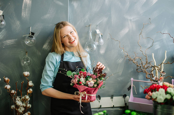 blond florist smiling to camera and resting at work - Fotó, kép