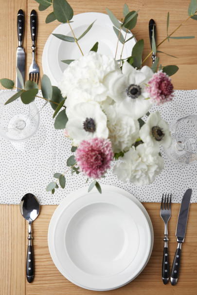 Mesa festiva con cubiertos y platos sobre mesa con flores
 - Foto, Imagen