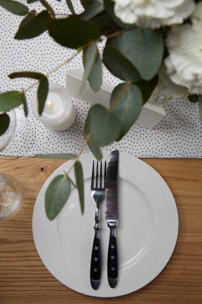 Table setting with cutlery on plate on table with flowers - Fotoğraf, Görsel