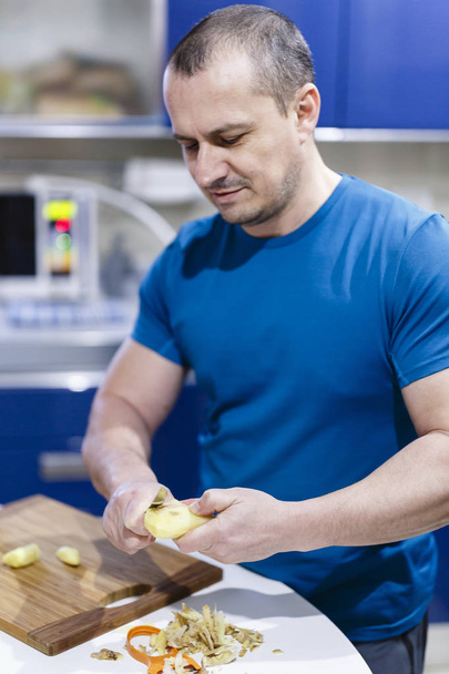 Adam mutfaktaki ahşap bir keresteyle sebze kesiyor. - Fotoğraf, Görsel