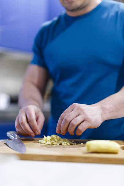 hombre corta verduras en una madera de madera en la cocina
 - Foto, Imagen