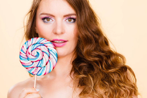 Woman holds colorful lollipop candy in hand - Foto, afbeelding