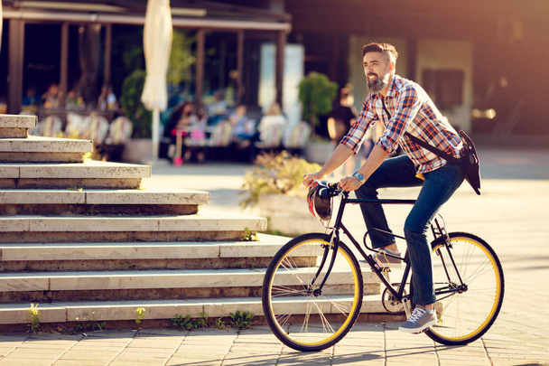 Smiling casual businessman going to work by bicycle. - 写真・画像