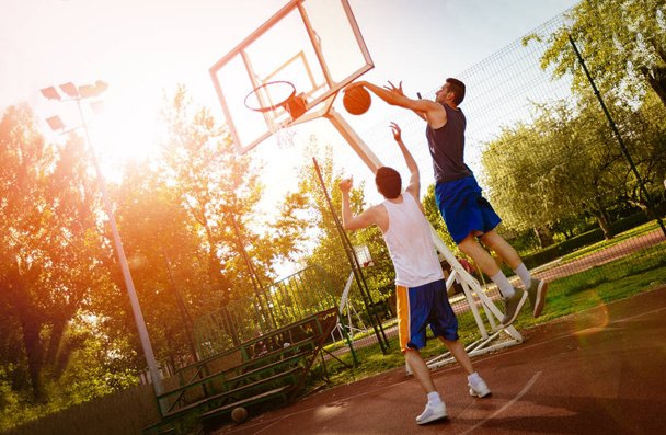 Dos jugadores de baloncesto callejeros entrenando al aire libre. Están haciendo una buena acción.
. - Foto, imagen