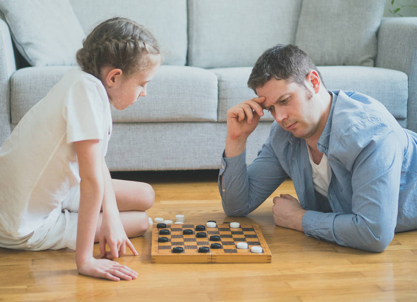 Father and daughter playing checkers board game. - Photo, Image
