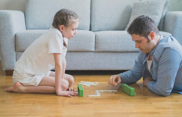 Vader en dochter spelen van Domino's thuis. - Foto, afbeelding