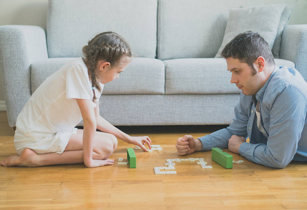 Isä ja tytär pelaavat dominoa kotona
. - Valokuva, kuva
