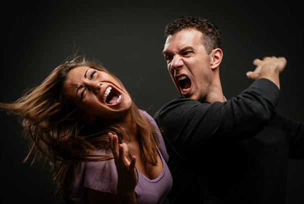 Θυμωμένος επιθετικός σύζυγος προσπαθεί να χτυπήσει τη γυναίκα του. - Φωτογραφία, εικόνα