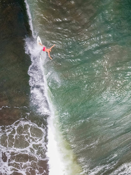 Der Surfer reitet und schwimmt auf dem Brett und seziert die Wellen des Ozeans. Tiefe und grenzenlose Ozeane. Luftaufnahme mit Kopierraum. - Foto, Bild
