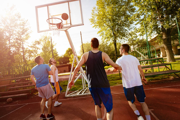 Quatre joueurs de basket-ball s'entraînent en plein air. Ils jouent et agissent ensemble
. - Photo, image