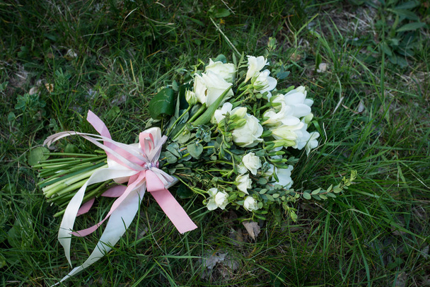 Wedding bouquet of white roses and greenery on green grass background. - Fotó, kép