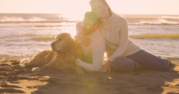Couple With A Dog enjoying time  together On The Beach at autumn day - Foto, imagen
