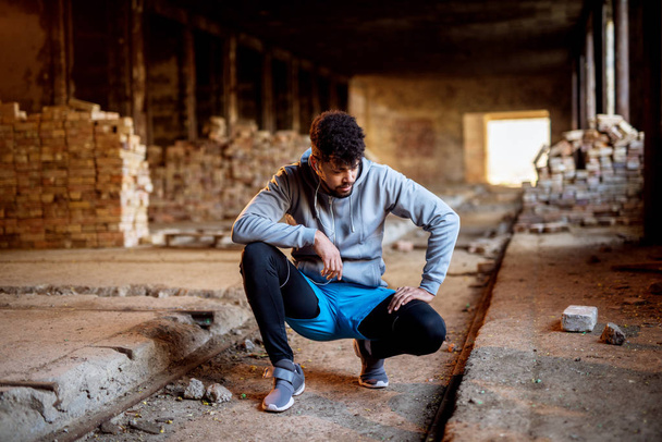 retrato de hombre afroamericano motivado entrenando en hangar abandonado con auriculares
 - Foto, Imagen
