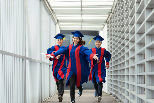 Portrait complet de diplômés joyeux avec des diplômes dans les mains courant vers une nouvelle vie pleine de merveilles
 - Photo, image