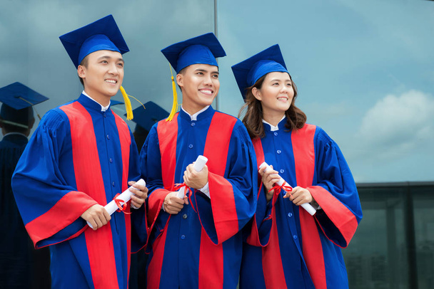 веселые вьетнамские студенты в выпускных платьях и шапках
  - Фото, изображение