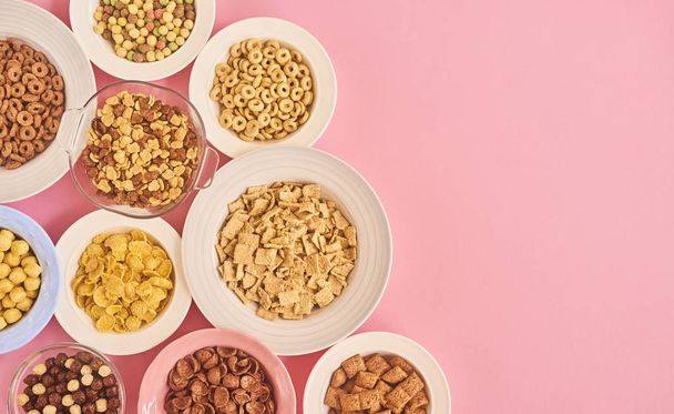 Different plates of cornflakes or cereals on pink background, top view - Foto, Bild