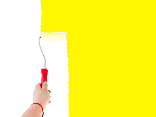 Una persona pintando una pared blanca con un cepillo de rodillo
 - Foto, Imagen