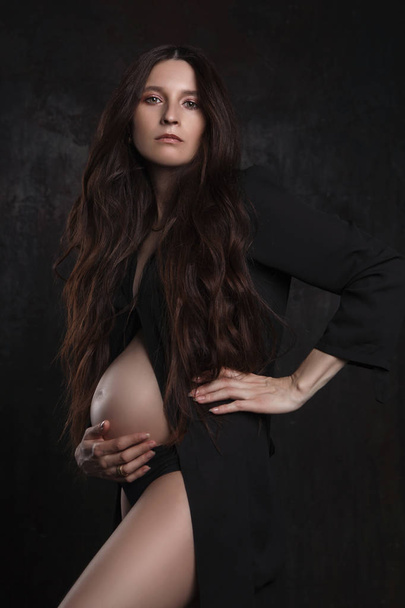 stylish portrait of pregnant woman on dark background - Fotó, kép