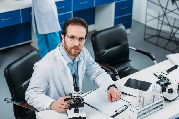 high angle view of scientist in white coat at workplace with microscopes in laboratory - Fotoğraf, Görsel