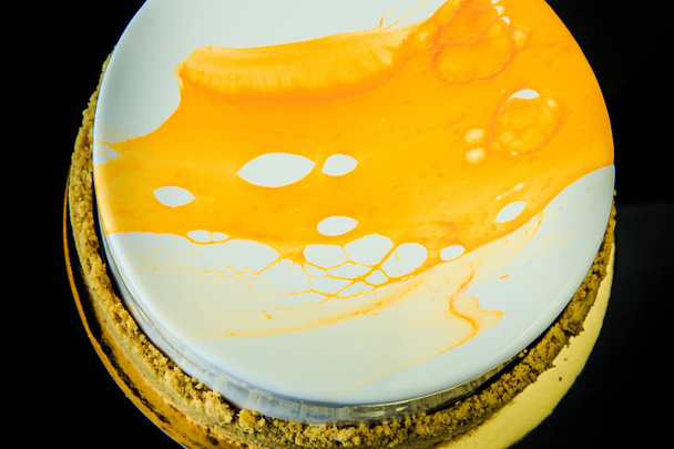 pastel de almizcle blanco casero pastel de almizcle recubierto con esmalte blanco y amarillo sobre fondo de espejo negro desde arriba
 - Foto, Imagen