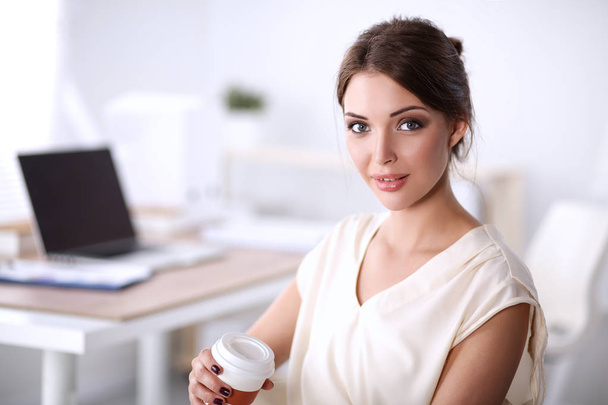 Portrait of beautiful happy smiling young designer woman sitting at home office with cup of coffee - 写真・画像