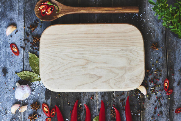 Top view of red chili peppers and cutting board on wooden surface background - Valokuva, kuva