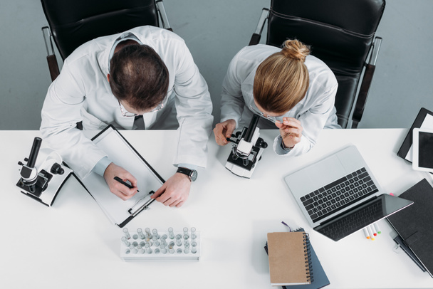 visão geral dos investigadores científicos em casacos brancos que trabalham em conjunto no local de trabalho em laboratório
 - Foto, Imagem