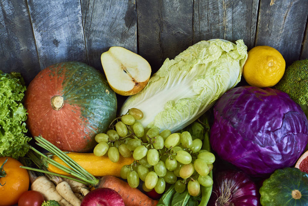 Состав с разнообразными сырыми органическими овощами и фруктами на деревянном фоне. Вид сверху
 - Фото, изображение