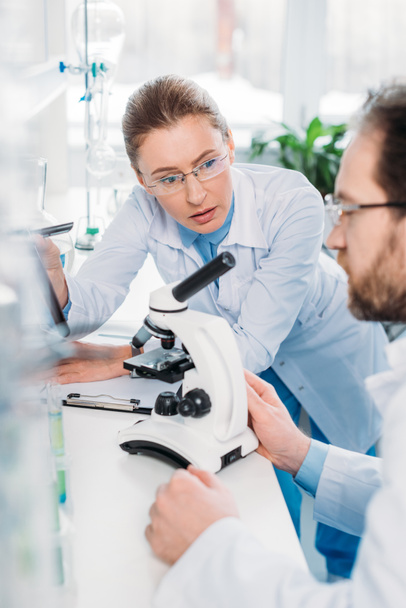 селективная направленность ученых в очках, работающих вместе на рабочем месте с микроскопом в лаборатории
 - Фото, изображение