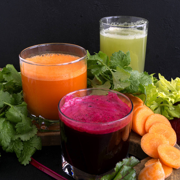 Vegetable juice in glass cups on a black background. Beets, cele - Photo, Image