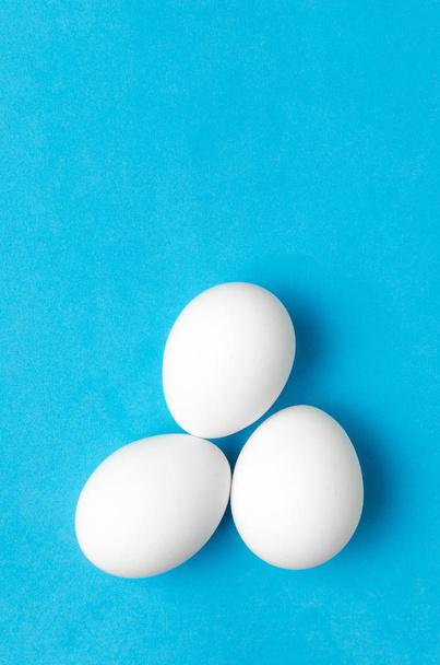 White chicken eggs on blue background. - Fotoğraf, Görsel