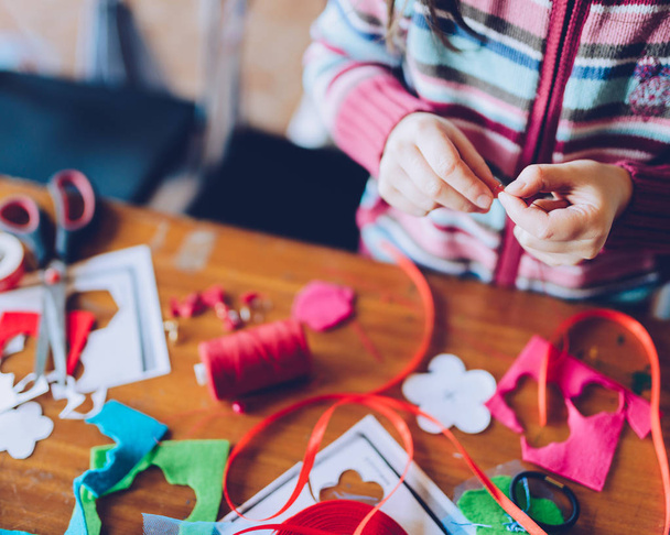 oficinas de arte sob medida para crianças - uma menina costurando decorações sentidas
 - Foto, Imagem