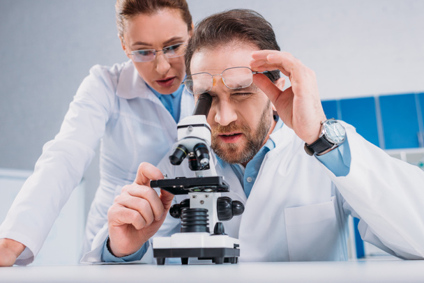 scientists in white coats and eyeglasses working with reagent together in lab - Foto, imagen