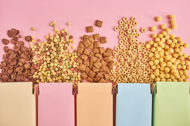 Boîtes colorées de flocons de maïs ou de céréales de différents types sur fond rose
 - Photo, image