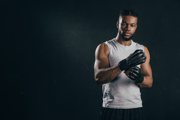 young african american kickboxer wearing gloves and looking at camera isolated on black - Fotografie, Obrázek