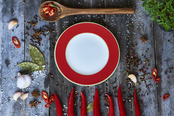 Top view of composition with red hot chili pepper corns, pepper pods and plate on wooden background.  - Photo, Image