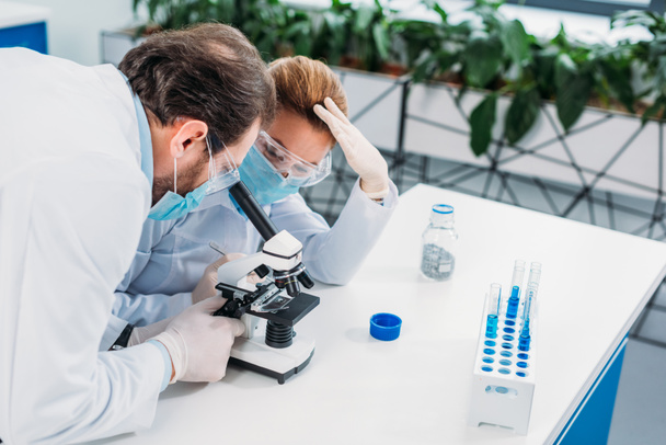 scientifiques en blouse blanche, gants médicaux et lunettes faisant de la recherche scientifique ensemble en laboratoire
 - Photo, image