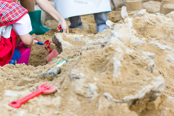 Los niños están aprendiendo restos de dinosaurios, excavando fósiles de dinosaurios simulación en el parque
. - Foto, imagen