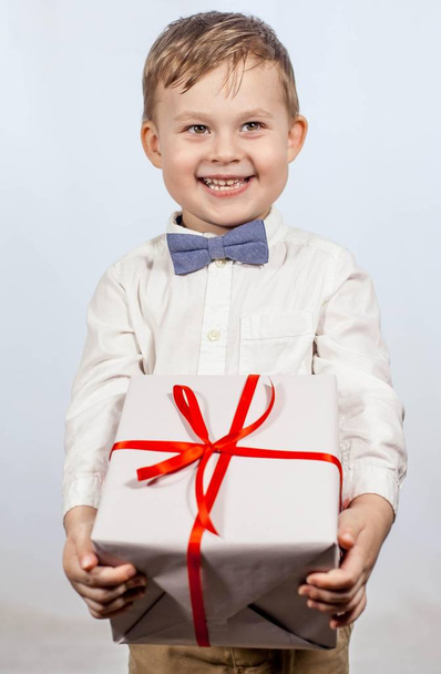 Cute little boy with a gift. Happy boy holding a box with a gift. Mothers Day. International Women's Day. Portrait of a happy little boy on a white background. Spring. Birthday. - Foto, immagini