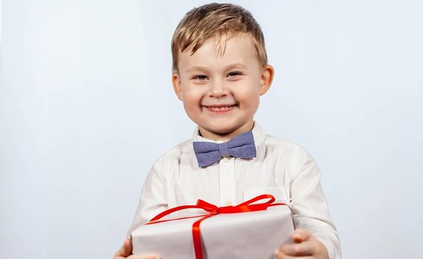 Cute little boy with a gift. Happy boy holding a box with a gift. Mothers Day. International Women's Day. Portrait of a happy little boy on a white background. Spring. Birthday. - Fotografie, Obrázek