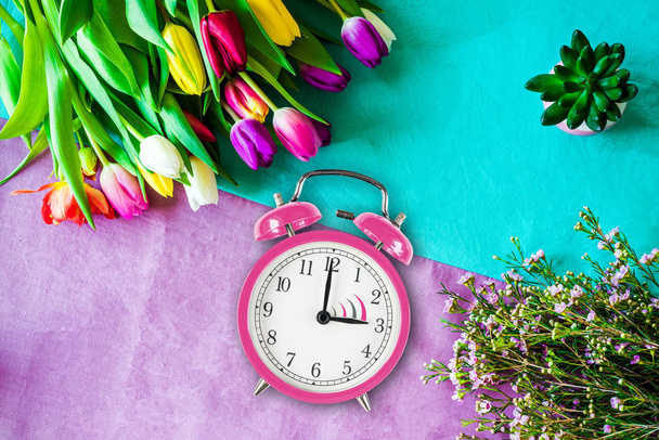 Switch to summer time on alarm clock with tulips and flowers fro - Fotó, kép