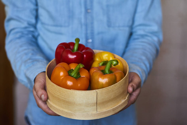 Крупный план мужских рук, держащих большую тарелку с перцем. Осенний сбор урожая и здоровые органические продукты
 - Фото, изображение