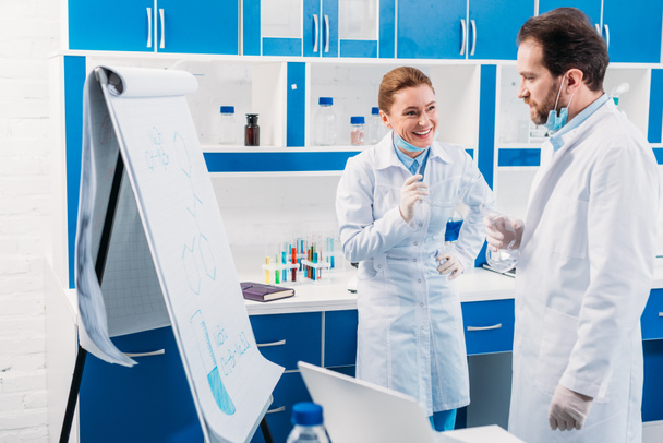 scientifique en blouse blanche près du tableau pour les notes en discussion pendant le travail en laboratoire
 - Photo, image