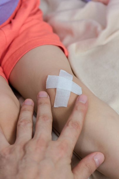 Perna de criança após acidente com a mão do médico e banda
 - Foto, Imagem