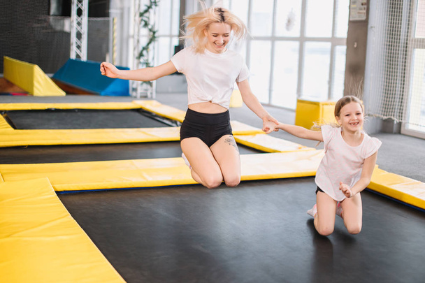 mother and daughter jumping on trampoline and doing split - Valokuva, kuva
