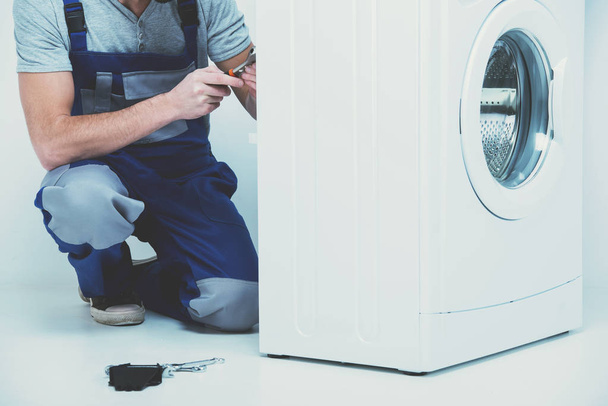 Repairman is repairing a washing machine on the white background - Foto, immagini