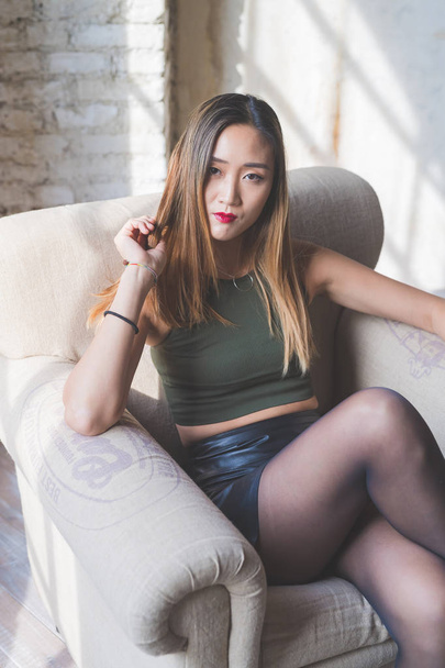 young woman indoors sitting armchair posing looking camera - attitude, blogger, influencer concept - Photo, Image